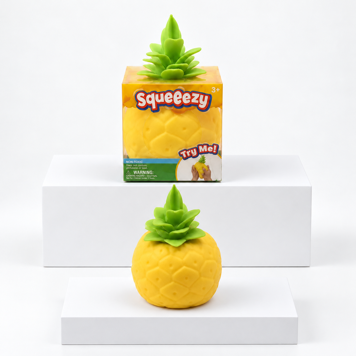 Yellow Squeeezy pineapple toy with green leaves pictured below its box
