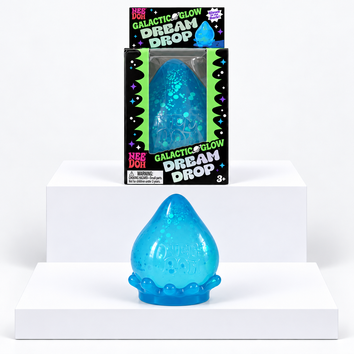 Blue NeeDoh Galactic Glow Dream Drop toy in front of its box on white display blocks