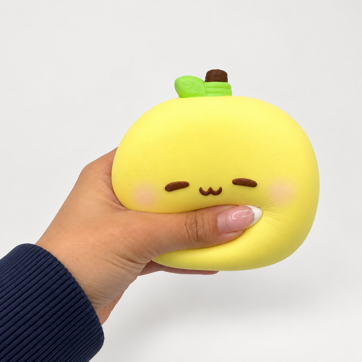 Hand holding and squeezing a yellow round Nunu character with a green stem