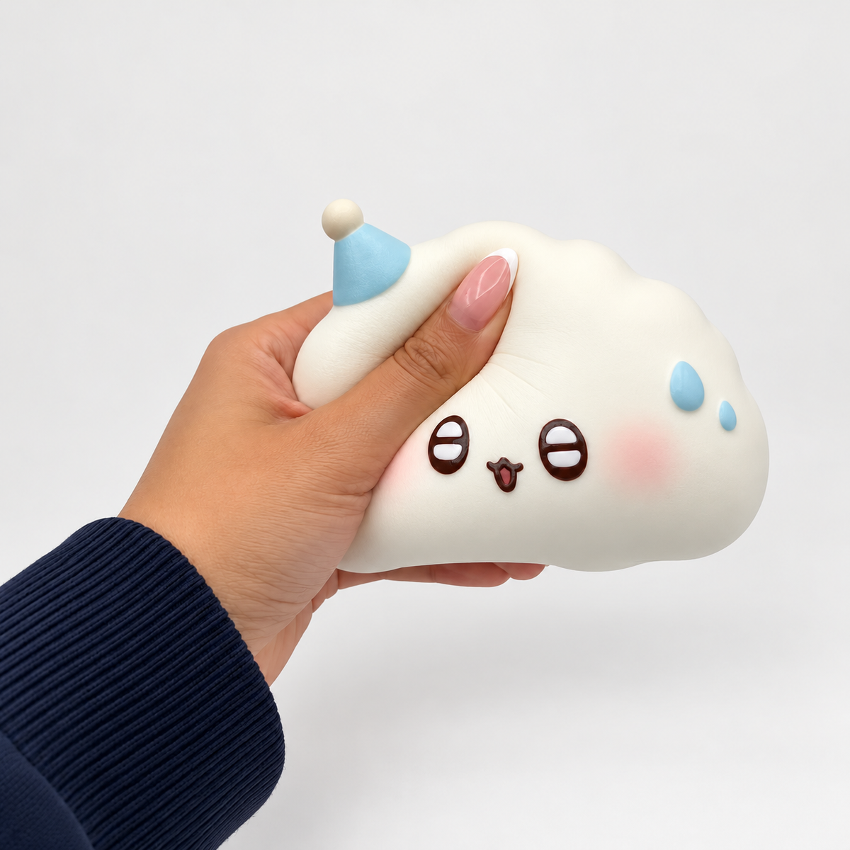 Hand squeezing a white Nunu cloud character with blue details