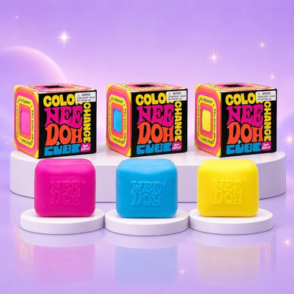 Squish Planet NeeDoh color changing cube fidget toys in pink, blue, and yellow with matching display boxes.
