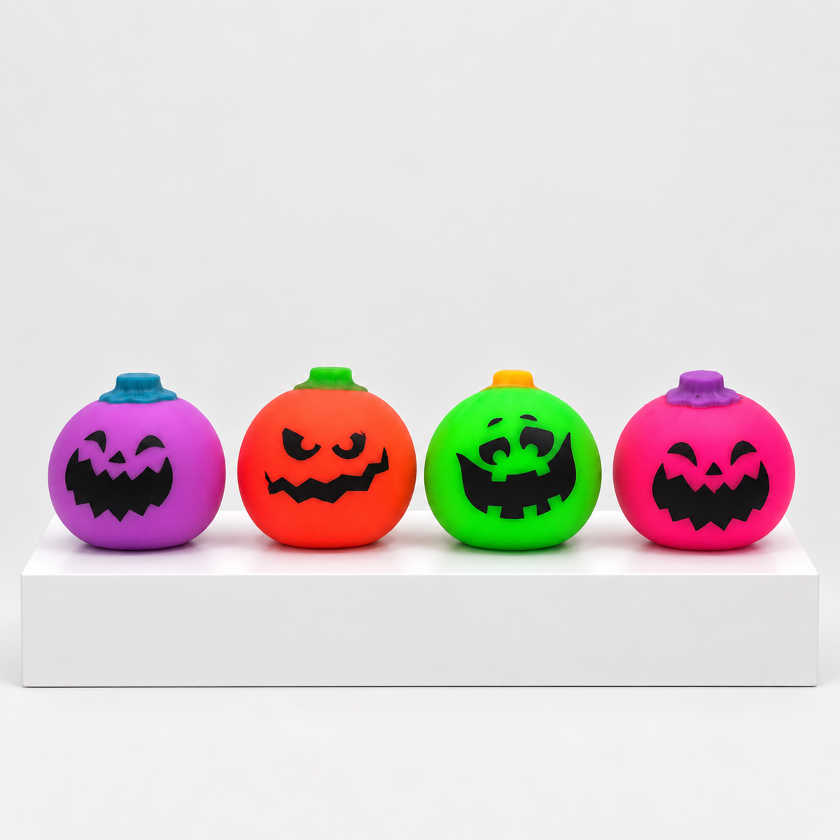 Four NeeDoh Jack-Glow-Lantern pumpkin squishies in purple, orange, green and pink