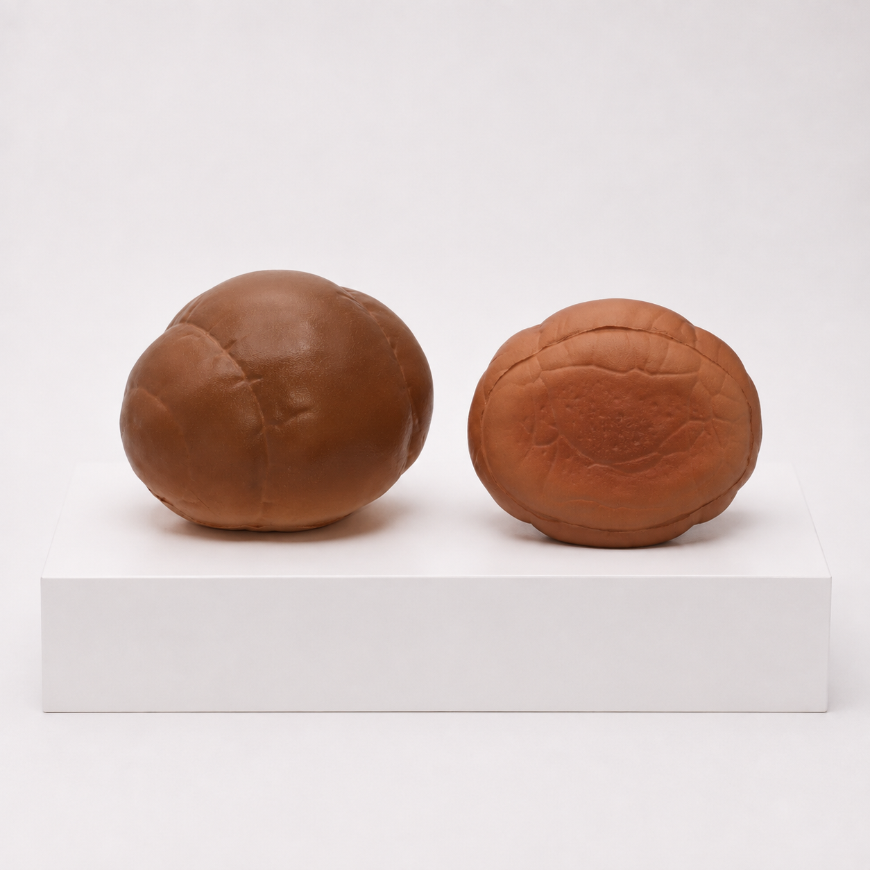 Two brown bread-roll squishies, one upright and one showing its underside