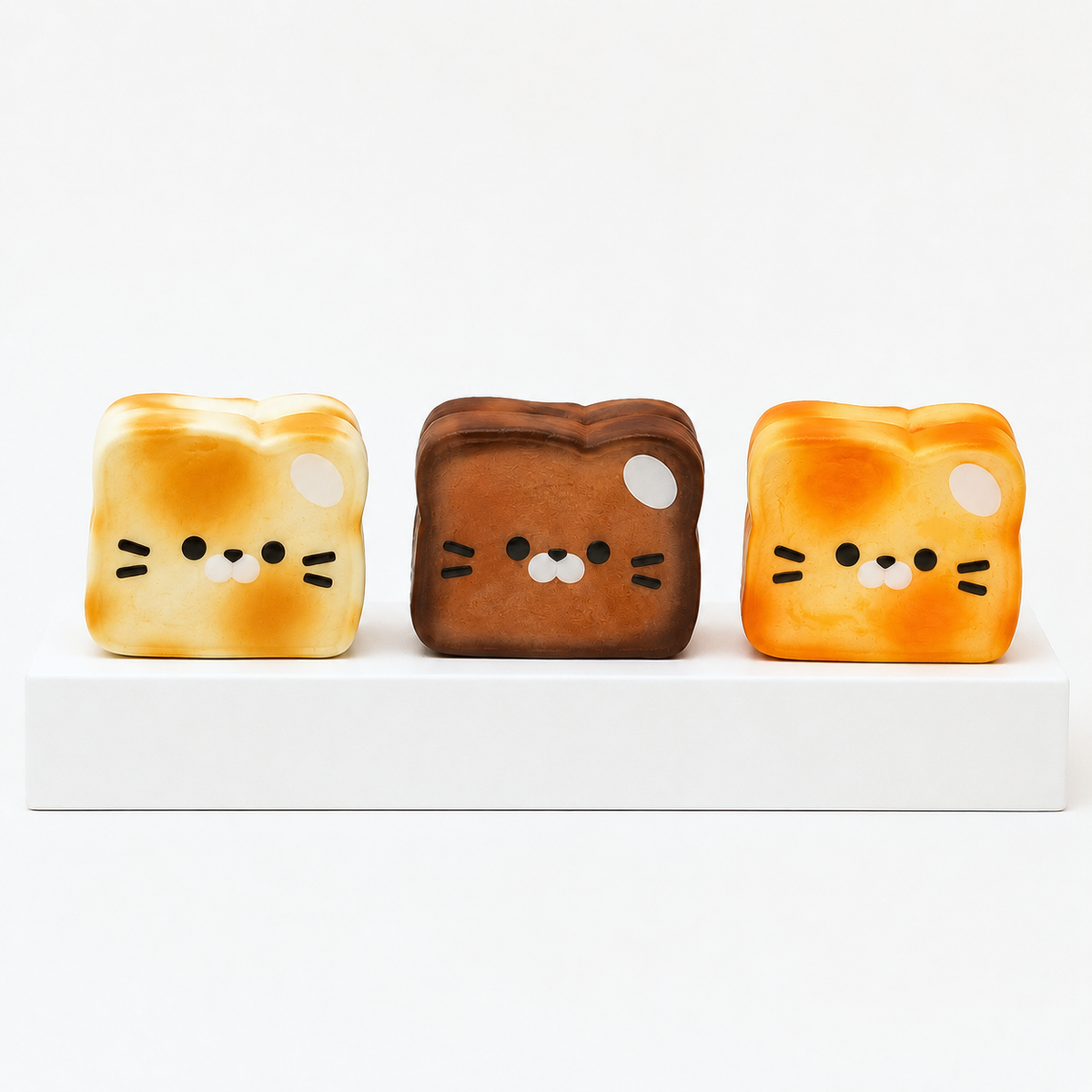 Three loose Kawaii Cat Yogurt Toast squish toys in cream, brown and orange