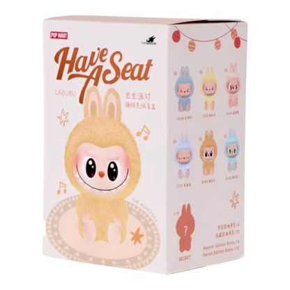 Pop Mart Labubu The Monsters Have a Seat Series blind box featuring a fuzzy yellow creature with big eyes, sitting on a rug. Includes collectible pendant figures.