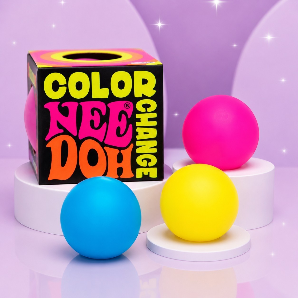 Squish Planet NeeDoh color changing squishy fidget balls in pink, yellow, and blue on white display pedestals.