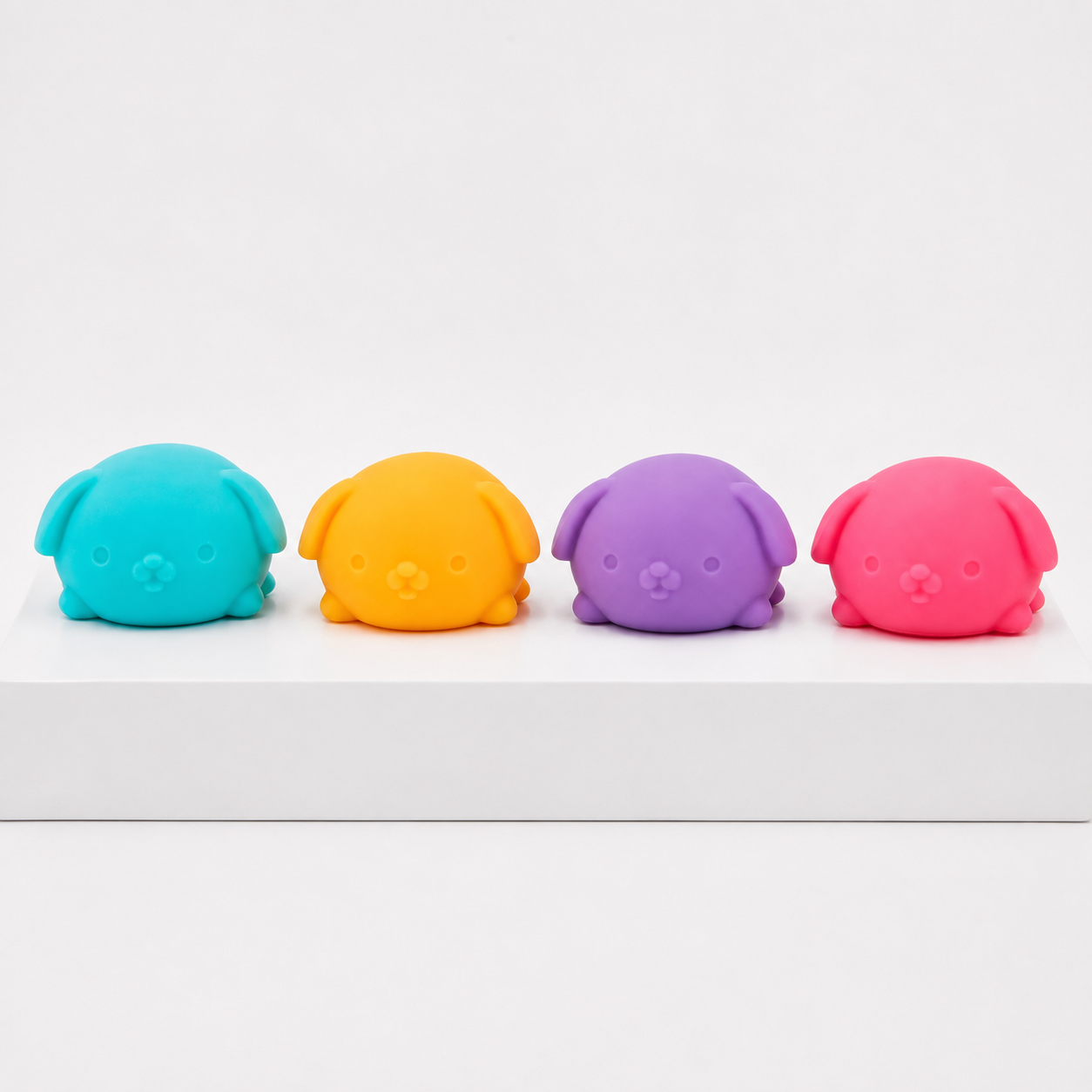 Four loose NeeDoh Funky Pup toys in blue, yellow, purple and pink