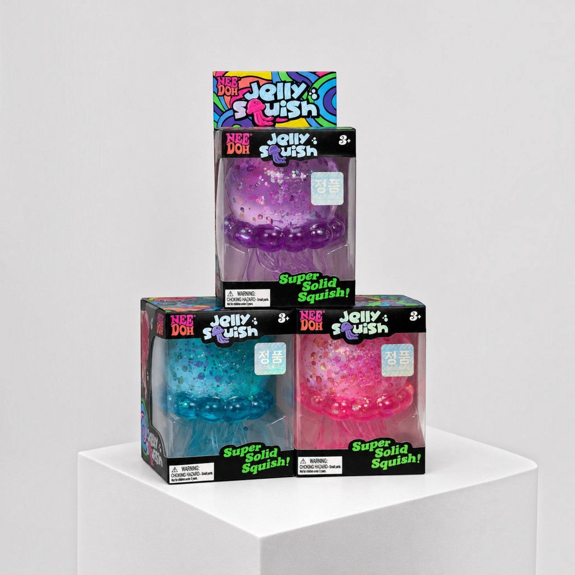 Squish Planet NeeDoh JellySquish fidget toys in purple, blue, and pink jellyfish designs inside retail packaging.