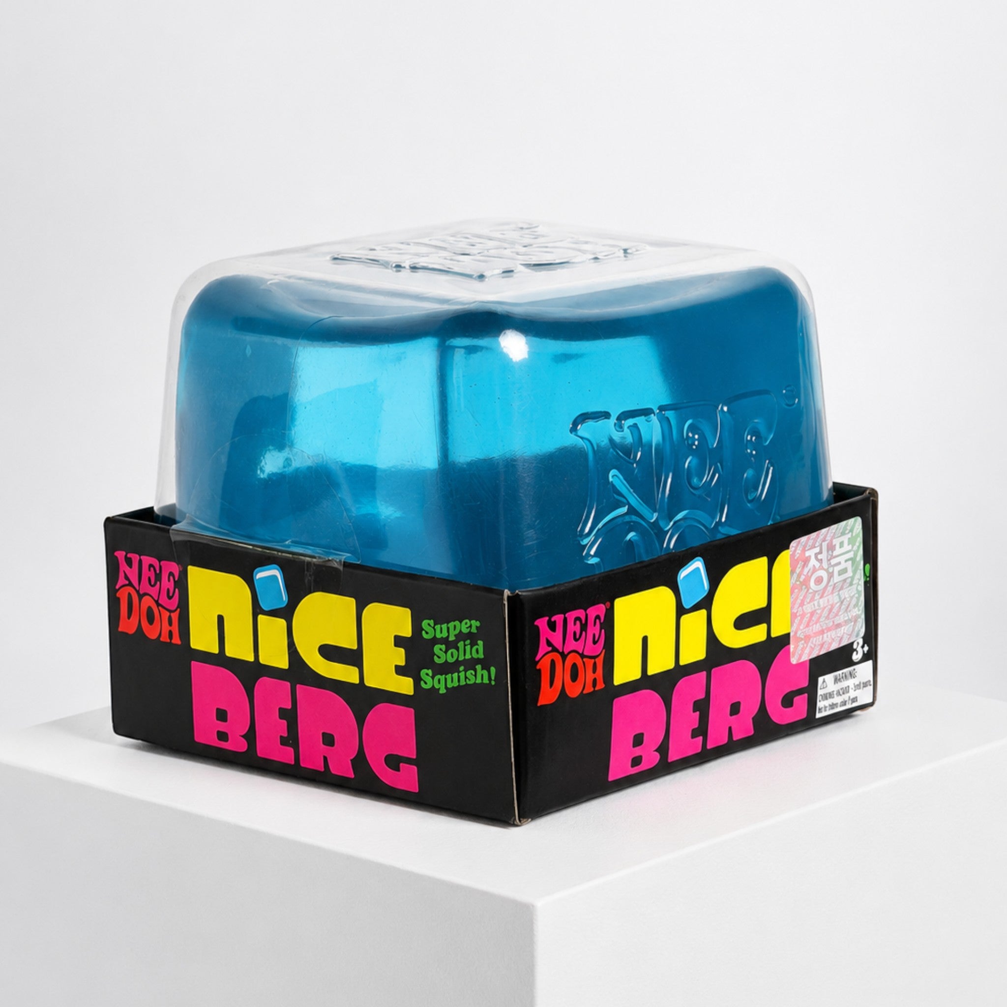 Squish Planet NeeDoh Nice Berg translucent blue ice-inspired cube squishy fidget toy in its display packaging.