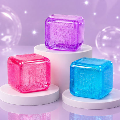 Squish Planet NeeDoh Nice Berg glitter and glow squishy fidget toy cubes in pink, purple, and blue on display stands.