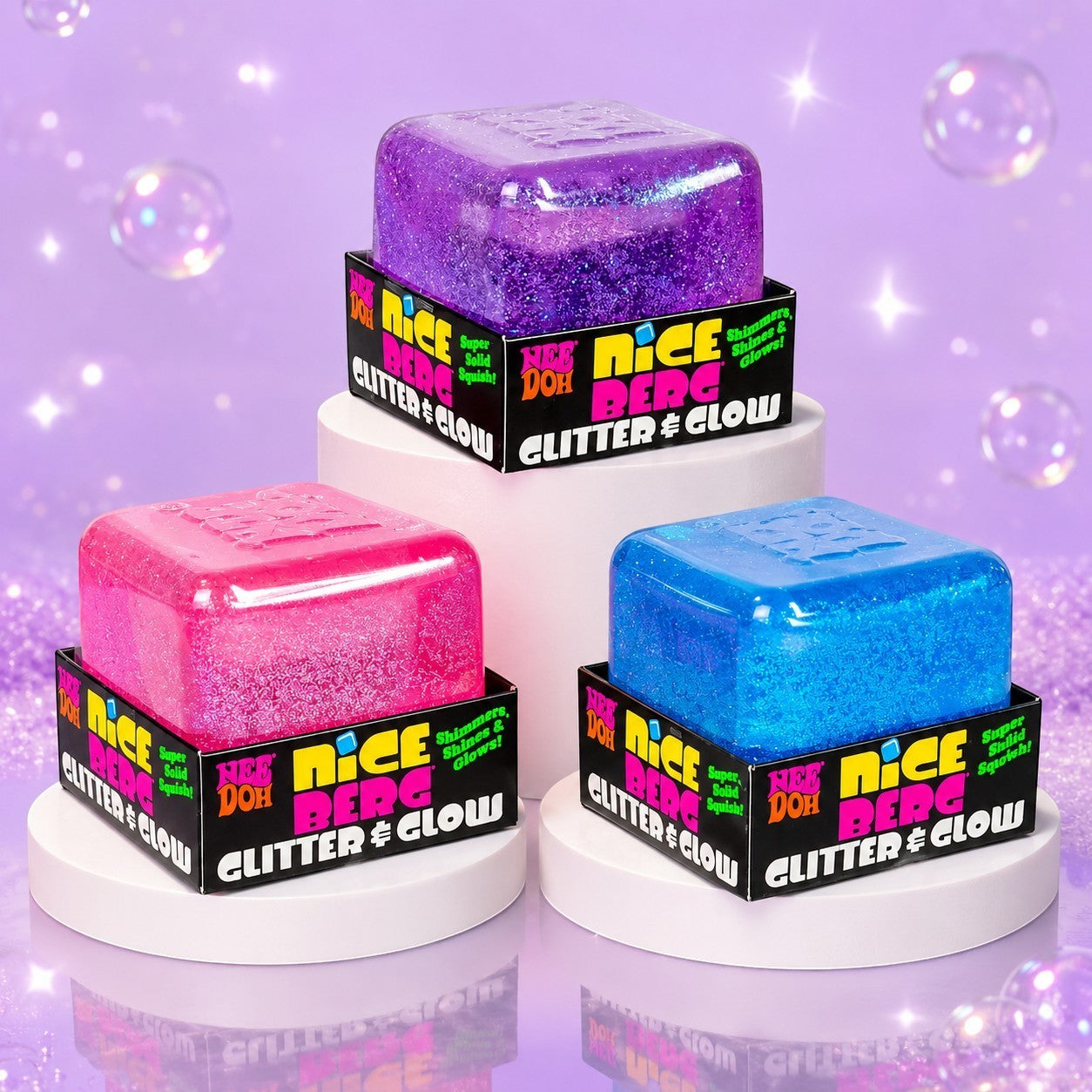 Squish Planet NeeDoh Nice Berg glitter and glow squishy cube fidget toys in purple, pink, and blue on display stands.