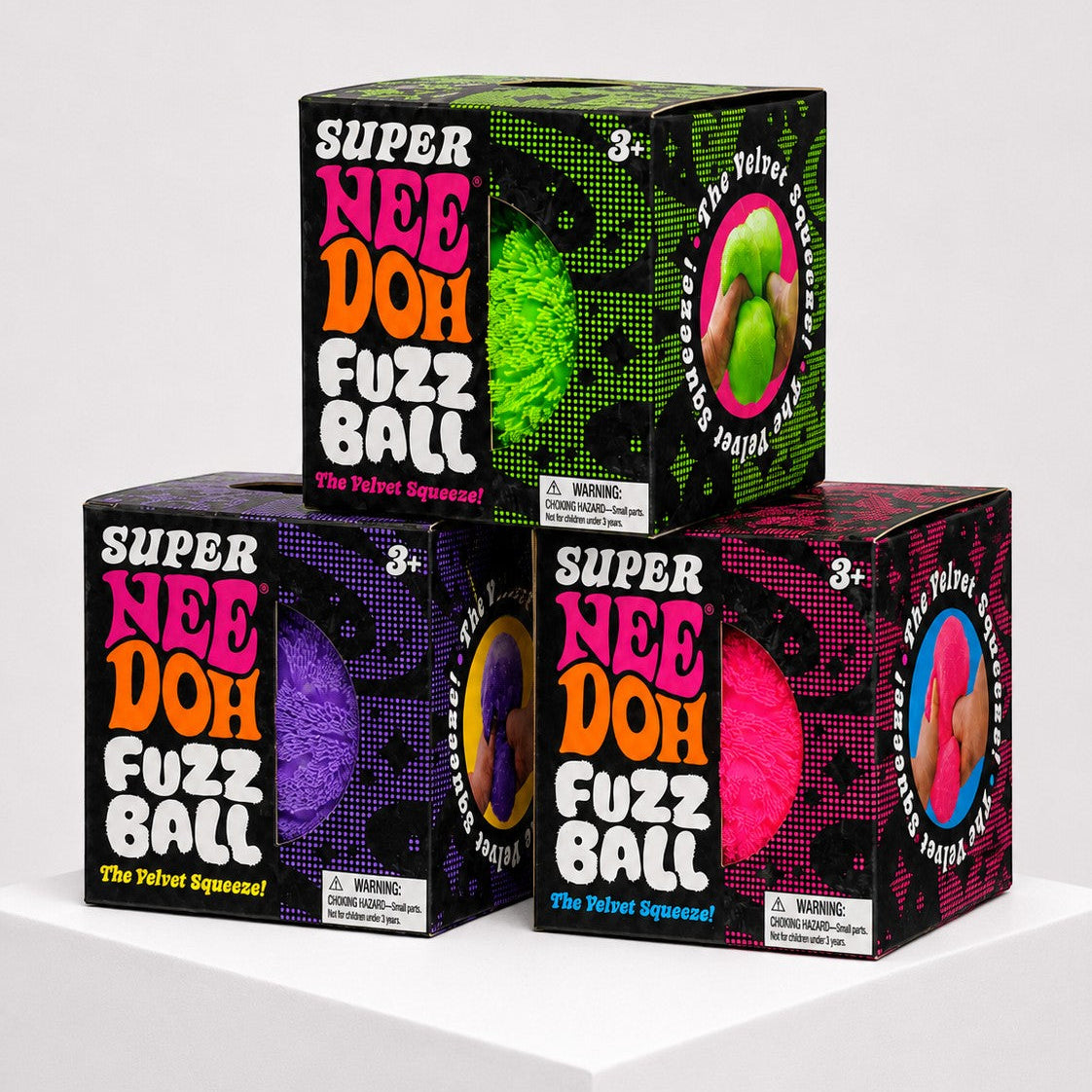 Squish Planet NeeDoh Super Fuzzball fidget toy boxes in green, purple, and pink on a white display stand.