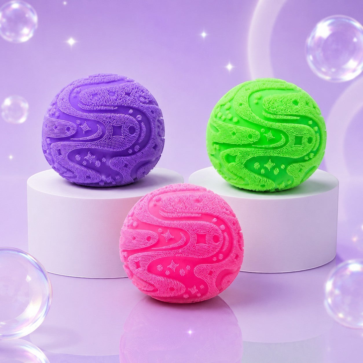 Squish Planet NeeDoh Super Fuzzball fidget toys in purple, green, and pink with raised sensory textures on pedestals.