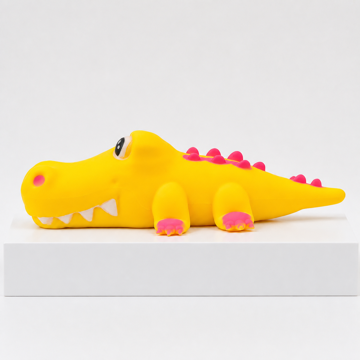 Yellow PPNC alligator squishy toy with pink feet and back spikes, side view