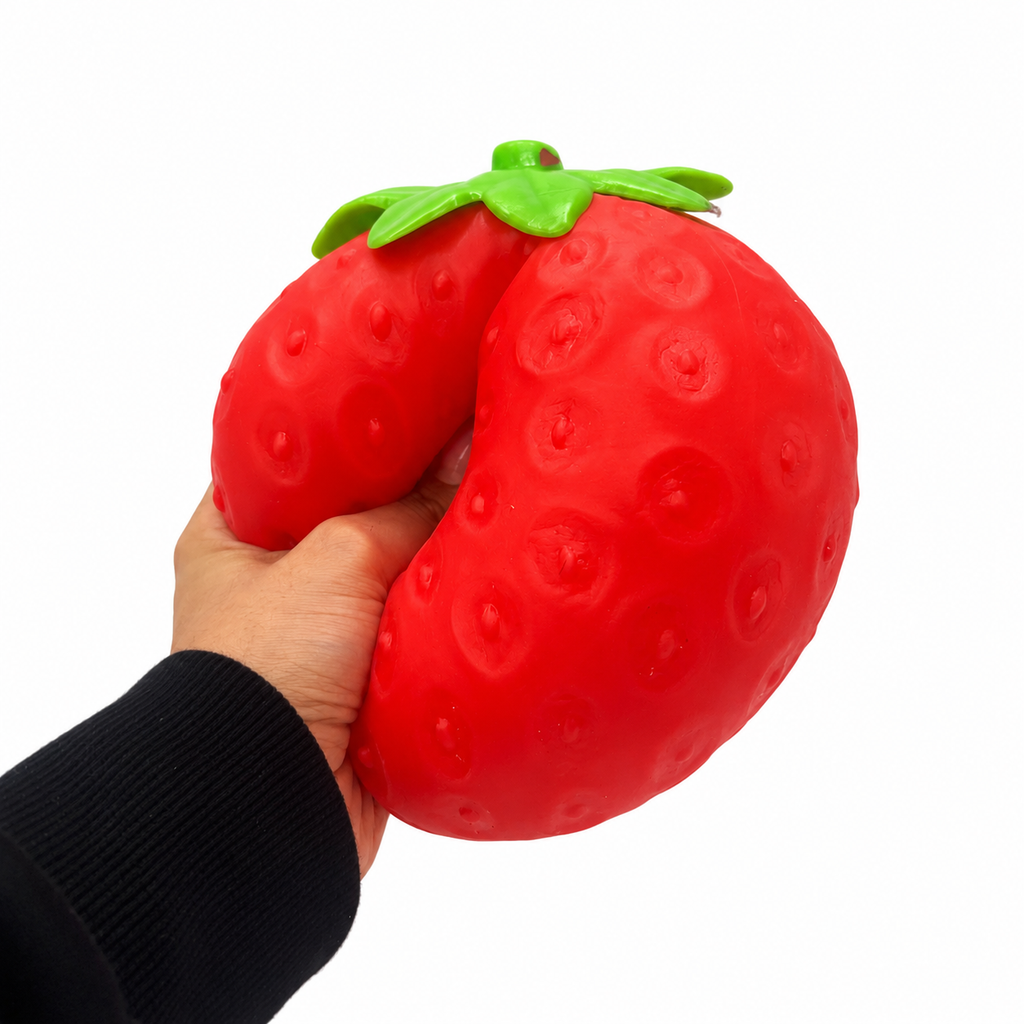 Hand squeezing a red Squeeezy Strawberry sensory toy