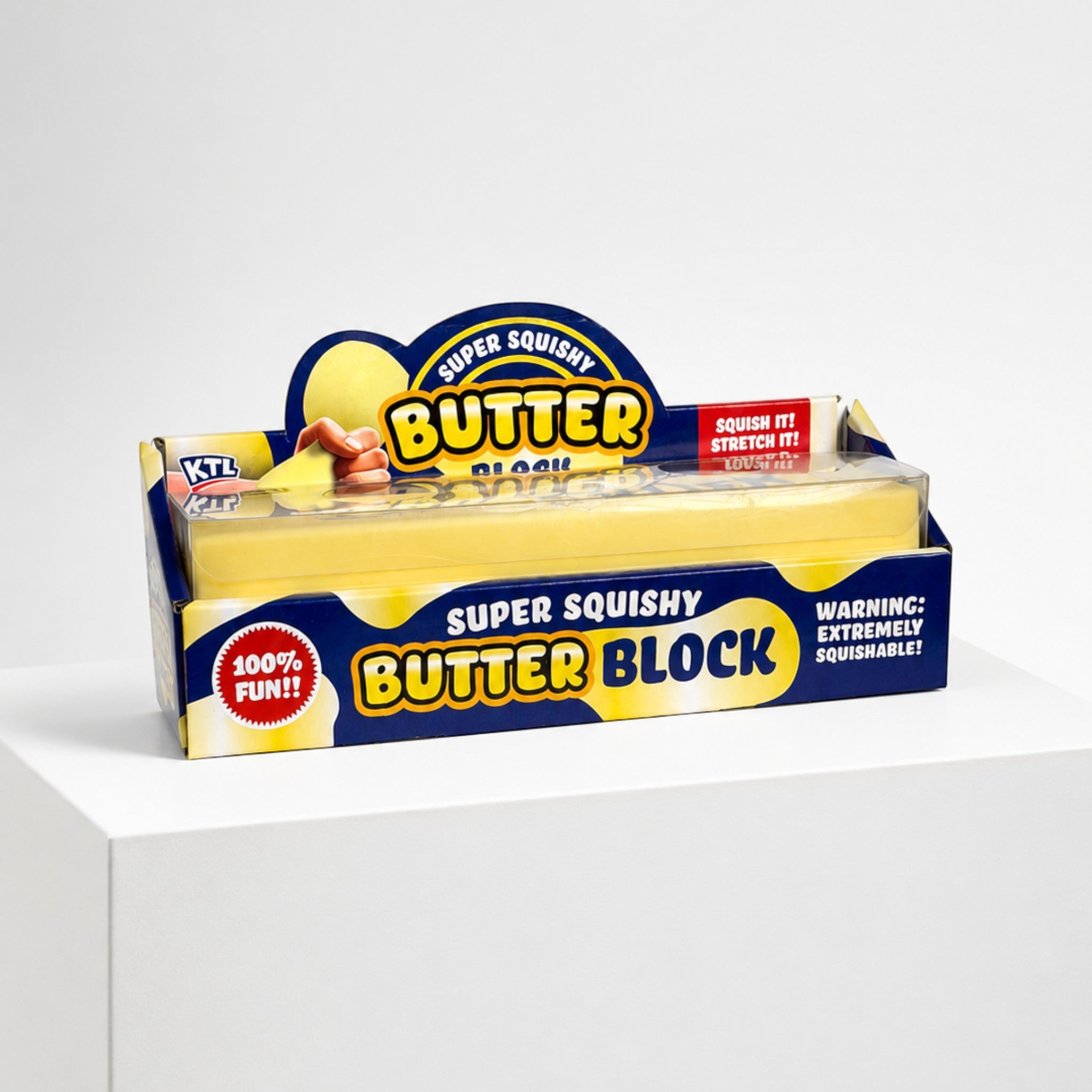 Squish Planet KTL jumbo butter block fidget toy in its original yellow and blue retail packaging on a white pedestal.